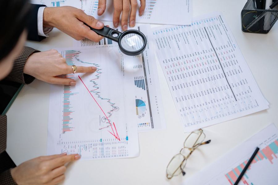 A magnifying glass held over financial documents and charts